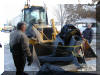 Stansbury Park Service Agency's Bob Shields and SLAS's Bruce Grim look on as the "Big Scope" mount is lifted from Bruce's driveway. SPSA's Colton Park is at the controls of the back hoe. Note the bicycle tire being ingeniously used to protect the polar shaft gear. 05 FEB 2002 Ron Ford image