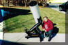 SLAS member Siegfried Jachmann poses next to the 1/3 scale model of the 81 cm (32") telescope to be installed in the Harmons Observatory at SPOC 2. Note the position of the eyepiece. As the telescope utilizes a Springfield mount the eyepiece remains in the same place regardless of where the telescope is pointed. 27 NOV 2000